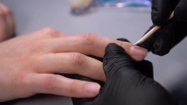 Siyah eldivenli bir kadının güzellik salonunda manikür üzerinde çalışmasını yakından izleyeceğiz.