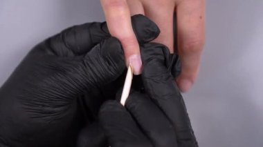 Siyah eldivenli bir kadının güzellik salonunda manikür üzerinde çalışmasını yakından izleyeceğiz.