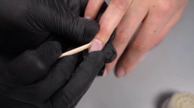 Siyah eldivenli bir kadının güzellik salonunda manikür üzerinde çalışmasını yakından izleyeceğiz.