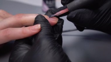 Siyah eldivenli bir kadının güzellik salonunda manikür üzerinde çalışmasını yakından izleyeceğiz.