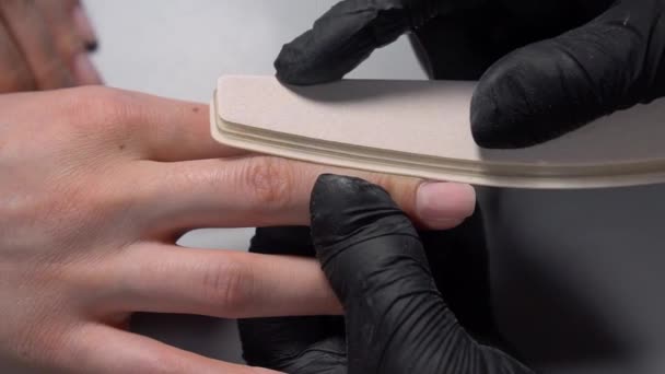 戴黑色手套的妇女手使用指甲文件来护理指甲 并为年轻女士做指甲修整 美容院 美甲制作 身体护理 艺术概念 — 图库视频影像