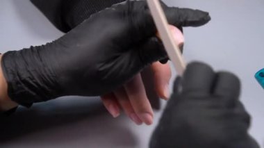 Siyah eldivenli bir kadının güzellik salonunda manikür üzerinde çalışmasını yakından izleyeceğiz.
