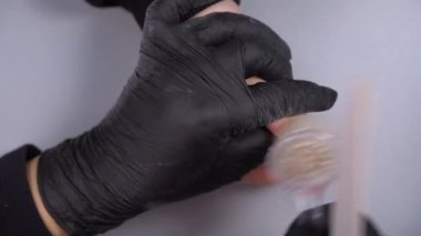 Siyah eldivenli bir kadının güzellik salonunda manikür üzerinde çalışmasını yakından izleyeceğiz.