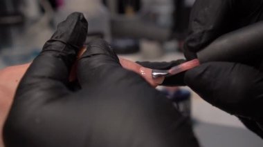Manikür yaptırmaya çalışıyorum. Güzellik salonu elleri ve tırnakları koyu bir arka planda. Video görüntüleri