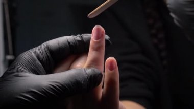 Siyah eldivenli bir kadının güzellik salonunda manikür üzerinde çalışmasını yakından izleyeceğiz.