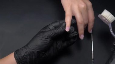 Siyah eldivenli bir kadının güzellik salonunda manikür üzerinde çalışmasını yakından izleyeceğiz.