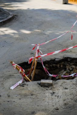 Kırmızı ve beyaz bariyerler tehlikeli bölgeyi koruyor. İnşaat alanı. Yıkımdan sonra yolun tamiri.