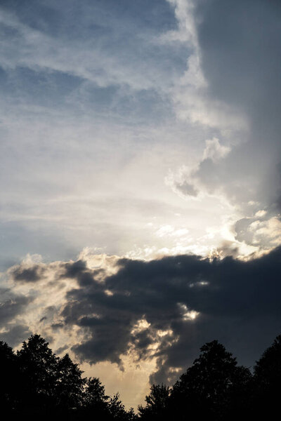 Dark, gloomy, stormy, rainy sky with rays of light. Terrible hurricane clouds. Background image for design