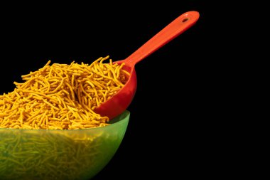 Açık Yeşil Kase 'deki Baharatlı Sev yığını, Namkeen Gıda, Nohut ve Baharatlar, büyük kırmızı kaşıkla.