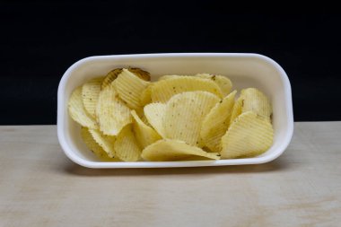 Tahta Masa 'da tuzlu patatesli gofret yığını, kopyalama alanı, cips yığını, yan görünüş, siyah arka planda izole edilmiş.