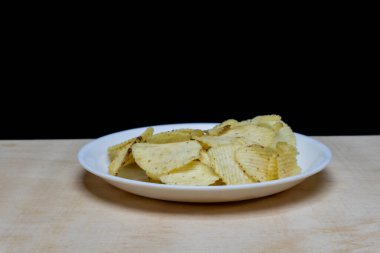 Tahta Masa üzerinde tuzlu patatesli gofret, bir yığın gofret, kopyalama alanı, cips yığını, yan görüş, siyah arka planda izole edilmiş.