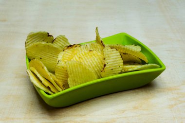 Tahta Masa 'daki Yeşil Kase' deki tuzlu patatesli gofretler, Yığınla gofret, Kopya Alanı, Cips Yığını, Yan Görüş