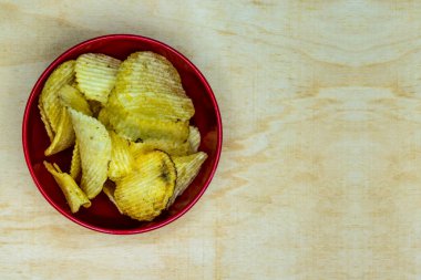 Tahta Masa 'da Büyük Kırmızı Kase' de tuzlu patates gofretleri, Çubuk Gofret, Kopya Alanı, Cips Yığını, Top View