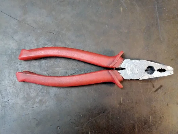 作業台に赤いハンドルを持つ作業用ペンチ — ストック写真
