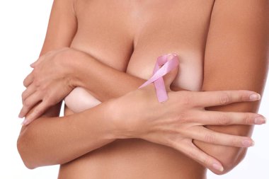 Bronzlaşmış bir kadın, eliyle göğüslerini kapatarak göğüs kanseriyle savaştığını gösterir. Beyaz arkaplanda stüdyo fotoğrafı