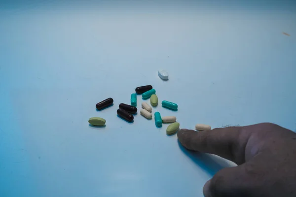 Dedo apontando pílulas soltas na mesa — Fotografia de Stock