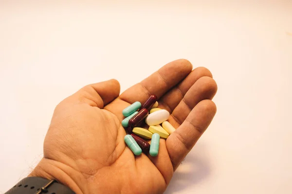 Mão mans segurando pílulas coloridas — Fotografia de Stock