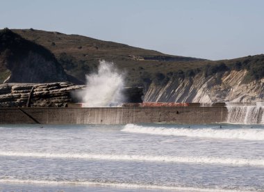 Dalgalar dalgalanan dalgalar dalgalanan su duvarına çarpıyor.