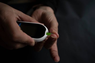 Glukometre kullanan, kan şekerini ölçen bir kadın..