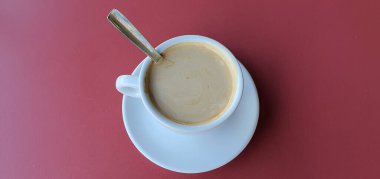 Kırmızı arka planda sütlü bir fincan kahve..