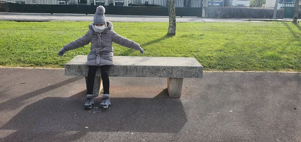 Chica sentada en un banco de piedra caliente para luchar contra el frío — Foto de Stock