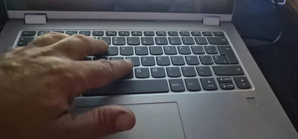 Şinde Beyaz Harflerle Gri Bir Bilgisayar Kullanan Birinin Eli — Stok fotoğraf