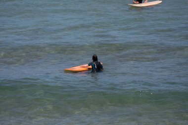 Guipuzkoa, Zarautz, İspanya - 09 Temmuz 2022: Zarautz plajlarında sörfçüler grubu. Bir grup sörfçü, spordan zevk alıyorlar, Bask kıyılarındaki güzel havadan faydalanıyorlar.