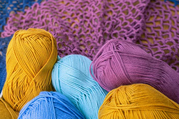 Sarı, pembe, açık mavi ve açık turkuaz iplik yumağı ve leylak örgü ağı. Çok renkli pamuk ipliği malzemesi kavramı.