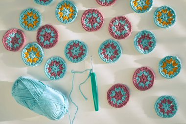 Örgü örgüsü kancası, zincir başlatıldı, iplik yumağı, beyaz yüzeyde küçük örgü çember motifler, koyu ışıkta koyu gölgeler, yan görüş. Çember örgü kalıpları oluşturma kavramı.