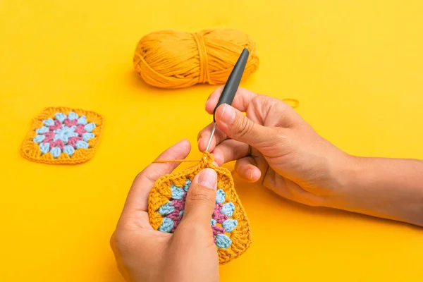 Closeup Woman Hands Hook Inserted Crochet Element Backgound Yellow Table — Foto de Stock