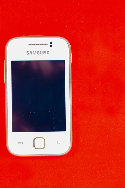 Wit Samsung Melkwegstelsel Jonge S5360 Smartphone Een Geïsoleerde Rode Achtergrond — Stockfoto