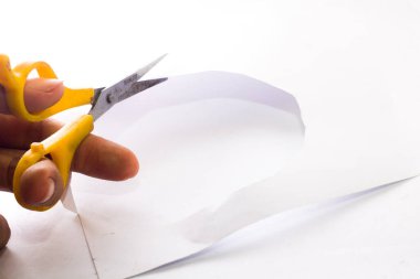 İzole edilmiş beyaz zemin üzerinde sarı makas kullanarak beyaz kağıdı kes. Güney Kalimantan, Endonezya. 12 Aralık 2021. 