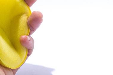 İzole edilmiş beyaz arkaplanı olan parmak üzerinde sarı sünger..