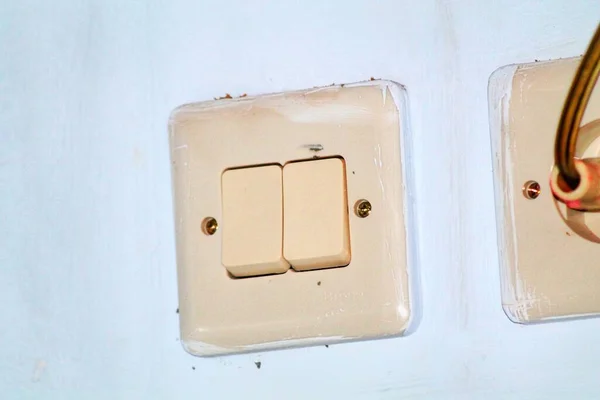 Gri duvarda beyaz ışık düğmesi.