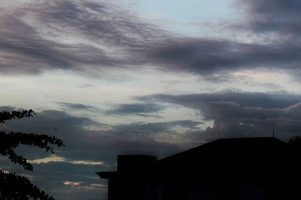 Bulutlu ve kara bulutlu bir binanın silüeti.