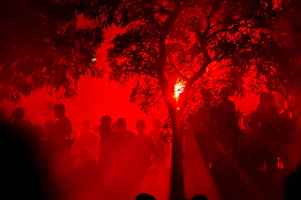 Yılbaşı gecesini kırmızı havai fişekleri izleyerek kutlayalım. İnsanların gölgeleri kırmızı ışıkta toplandı. Kırmızı arkaplanda siluet.