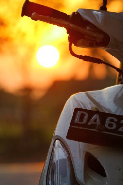 Güzel bir gün batımında arka planı bulanık, otomatik motorsiklet gidonu. Güney Kalimantan, Endonezya. 21 Ekim 2013. 