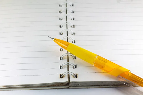 Boş bir defterdeki sarı kalem. Açık Not Defteri 'nin kalemle en üst görünüm minimal tasarımı. 