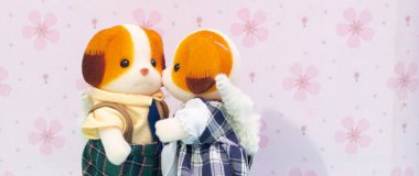 Pembe arka planda oyuncak bebek köpeği öpen bir kadın. Romantik bir an. Romantik aşk. Sevgililer günü, Noel günü, düğün ve aile günü için kopya alanı. 