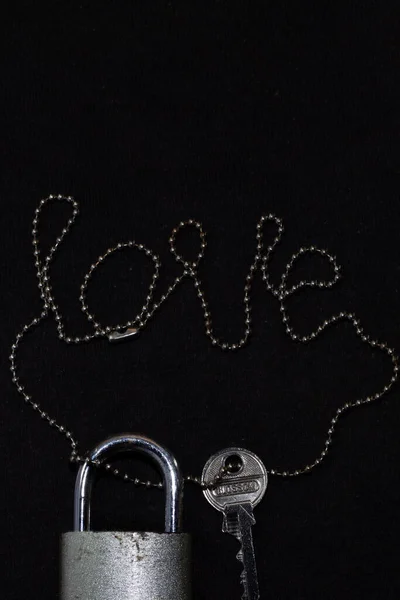 Zincirli kilit ve anahtar, izole edilmiş siyah bir arka planda aşk kelimesi. Düğün için fotokopi alanı, sevgililer günü, aşk, ilişki ve çift. Güney Kalimantan, Endonezya. 19 Mart 2014.
