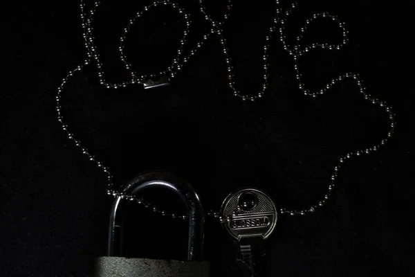 İzole edilmiş siyah bir arka planda kilit ve anahtarla aşk sözcüğünü taşıyan bir zincir. Düğün için fotokopi alanı, sevgililer günü, aşk, ilişki ve çift. Güney Kalimantan, Endonezya. 19 Mart 2014.