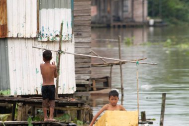 Çocuklar nehirde yıkanıyor. Asyalı çocuk. Banliyö çocuklarının günlük hayatı. Fakirlerin hayat portresi. Gecekondu yerleşimleri. Güney Kalimantan, Endonezya. 28 Şubat 2014.