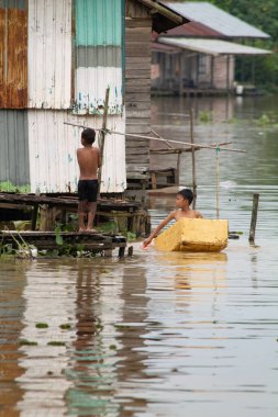 Çocuklar nehirde yıkanıyor. Asyalı çocuk. Banliyö çocuklarının günlük hayatı. Fakirlerin hayat portresi. Gecekondu yerleşimleri. Güney Kalimantan, Endonezya. 28 Şubat 2014.