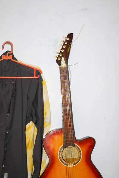 Duvara yaslanmış gitarlar ve bir elbise askısı. Müzik ve enstrümanlar için kopyalama alanı. Güney Kalimantan, Endonezya. 30 Kasım 2013.