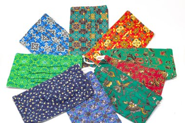 İzole edilmiş beyaz arka planda renkli batik maskeler. Sağlık, gardiyanlar, moda ve giysi aksesuarlarının kopyalama alanı.