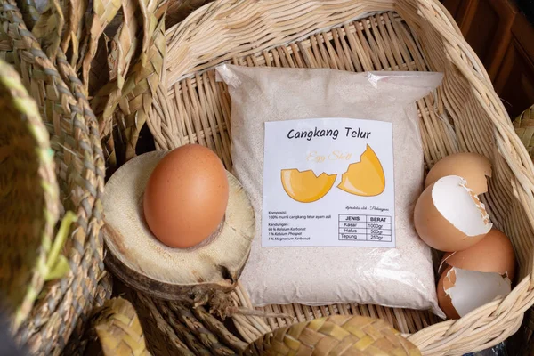 Tavuk yumurtası, tavuk yumurtası kabuğu, hasır bir arka plan olarak rattan sepetli tavuk yumurtası kabuklarından un. Güney Kalimantan, Endonezya. 26 Mayıs 2022.