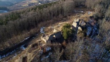 Ormanlarla çevrili bir tepedeki eski bir şatonun kalıntıları, güneşli havalarda turist ziyaretçileri - insansız hava aracı manzarası