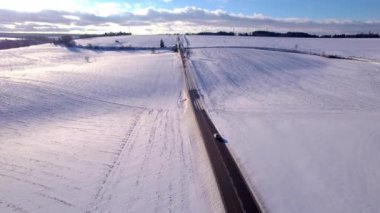 Yokuş yukarı, ufukta rüzgar türbinleriyle yol alan hareket halindeki bir araba.