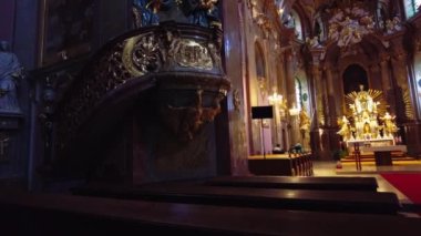 Decorated pulpit with gold, in the background an altar lit by candles to which I lead a red carpet between the benches, Bazilica Minore Navtven Panny Marie na Svatm Kopeku