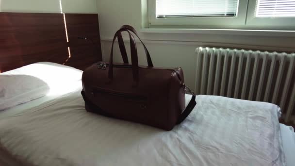 Brown Leather Bag Sits Hotel Single Bed Morning Light Window — Stockvideo